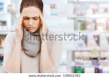 More than just a headache. Closeup portrait of a young female customer rubbing her temples while buying medicine at the drugstore