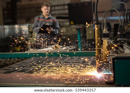 CNC Laser Plasma. Selective focus on laser plasma cutting of metal modern technology in process at metalworking manufacturing plant male worker on the background copyspace