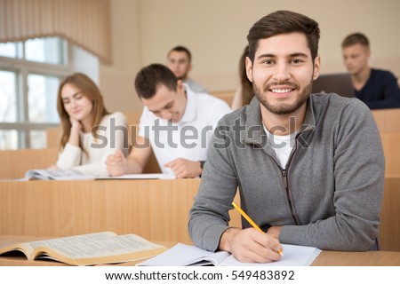 Putting in the effort. Handsome young guy smiling to the camera during the lecture at his university studying in the classroom happiness smart education exam college high school concept copyspace
