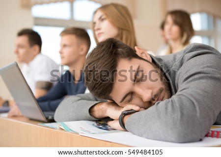 Too tired. Handsome male tired student sleeping on his books during lecture at university classroom exams session tired education lazy boring college sleep people school napping overworking concept