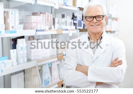 Successful small business owner. Cheerful senior pharmacist smiling to the camera while working at his drugstore profession doctor chemist pharmaceuticals medical health concept