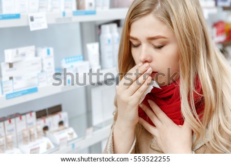 This flu is getting to her. Young woman coughing covering her mouth with a tissue buying medications at the pharmacy copyspace cough coughing sick ill cold flu seasonal healthcare people concept