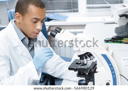 Biology pro. Handsome African man examining glass slide samples while working at his lab microscope biotechnology study research profession medicine immunology virus equipment microbiology concept