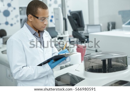 Medical research. Professional chemist young African man writing on his clipboard while working at the laboratory ethnicity profession occupation people medicine clinical biology internship copyspace