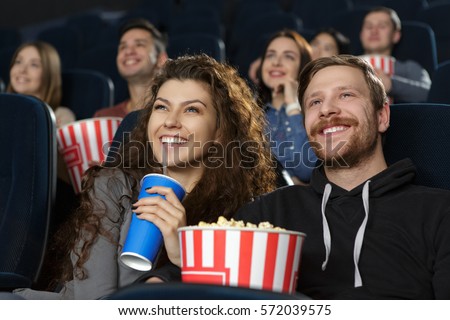 Date night at the cinema. Happy loving young couple smiling cheerfully enjoying a comedy movie together at the cinema love happiness relationships dating togetherness youth entertainment weekend