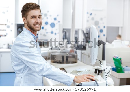 Computer at the lab. Young man working at the medical laboratory using computer to operate analyzing machines copyspace modern technology research science chemistry pharmaceutical medicine job concept