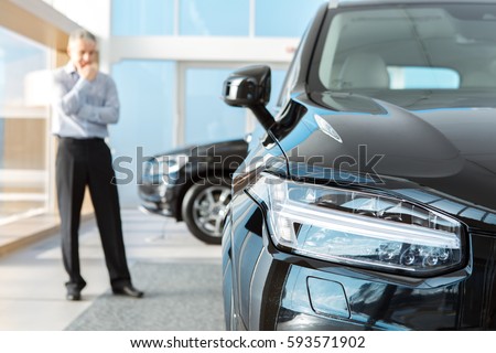 Choosing wisely. Selective focus on a car mature businessman standing thinking choosing a new car at the dealership copyspace choice decision business choosing buying a car consumerism purchase sales