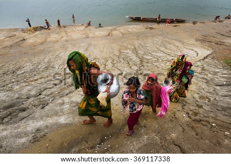 SYLHET, BANGLADESH- APRIL 04, 2015: An old woman with her family members was coming back to her house after collecting drinking water from nearby river.
