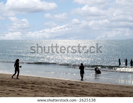 Beach landscape at sunrise with people playing near the sea