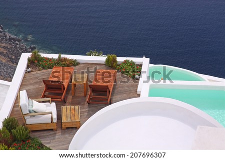 Terrace with deck chairs and a water pool. View to the sea in Santorini island, Greece