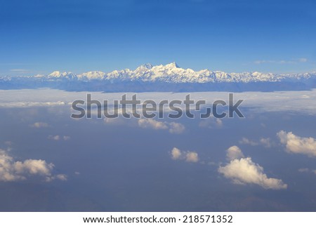 View through aircraft window at Himalayan mountains. Above the clouds