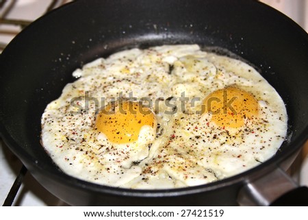 Spicy fried eggs in pan, sunny side up