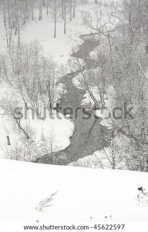 Winter creek between the snowdrift. Snowfall