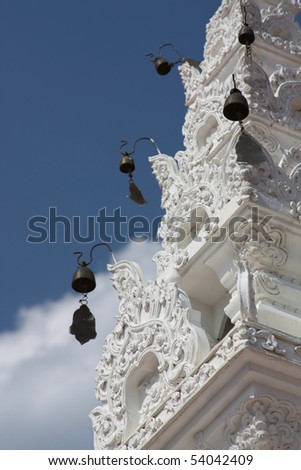 Wind-bells on a carved white tower in a Buddhist temple in Thailand