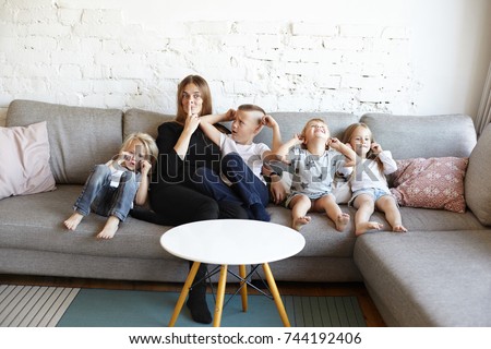 Big family of three spoiled little boys and one girl fooling around, crying and covering ears, their confused mother going crazy, making faces instead of calm them down. Single mother of many kids