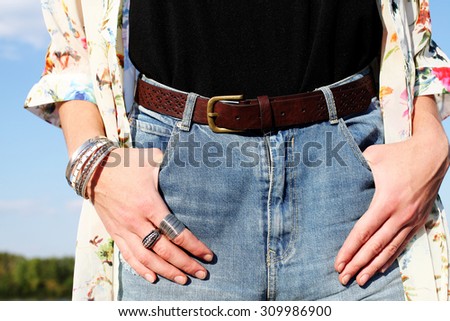 stylish girl in denim shorts with a high waist. hands with bracelets and rings close up. boho chic vintage outfit