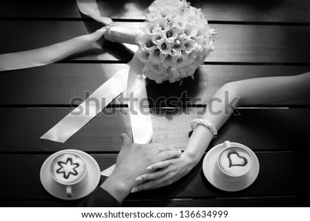 Man and woman\'s hands and coffee cups on the table, black and white