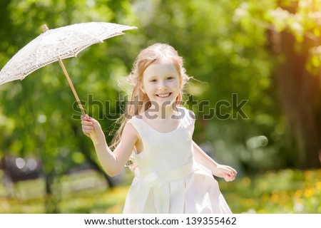 girl with a summer lace umbrella playing in the park