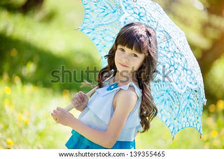 little girl with blue lace umbrella walks in the park