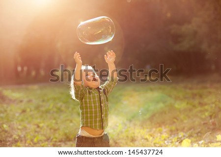 Little Boy In The Sunset Catches Soap Bubbles
