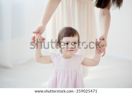 little girl first steps with the help of mom