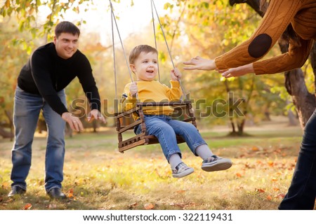Happy family having fun on a swing ride at a garden a autumn day