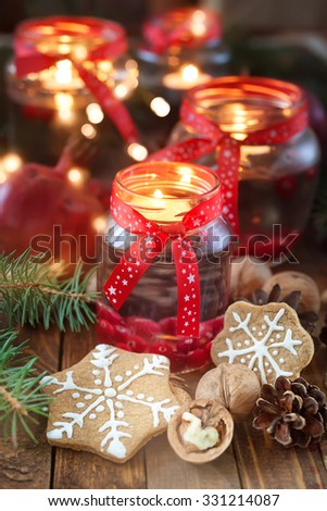 Christmas decorations. Candles in glass jars with fir and gingerbread cookies