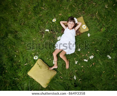 little girl resting on soft pillow in fresh spring grass