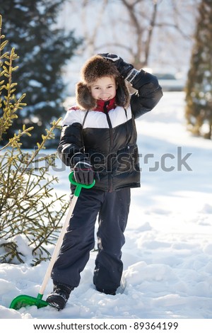 The boy cleans snow near to the house