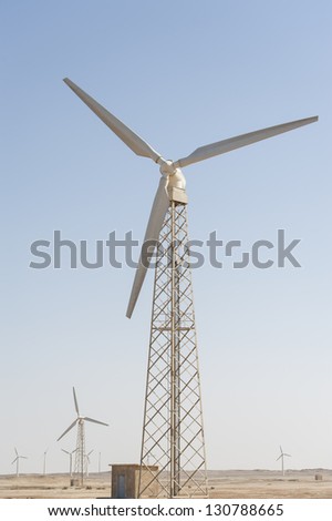 Electric wind turbine generators in the desert against a blue sky background