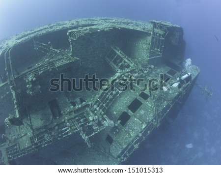 Scuba diver exploring a large sunken underwater shipwreck