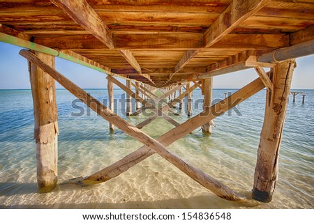 HDR image of a wooden jetty stretching out to sea from tropical desert island
