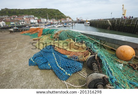 Trawler commercial fishing nets lying on quayside of english harbour