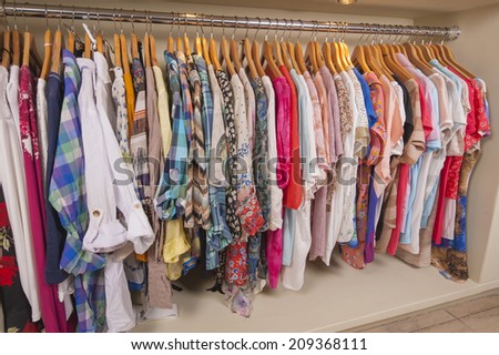 Variety of colorful womens clothing hanging on rail in fashion shop