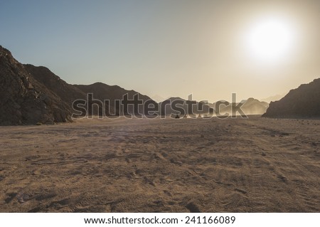 Group of quad bike atv vehicles traveling through rocky desert on safari with sunset