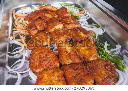 Closeup detail of grilled tawa fish curry on display at an indian restaurant buffet