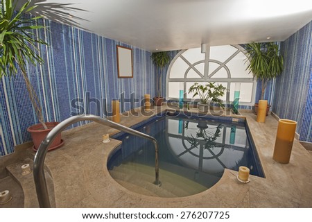 Large jacuzzi pool in room of luxury health spa center with candles