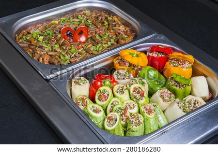 Closeup detail of dolma stuffed vegetables and green beans on display at an oriental restaurant buffet