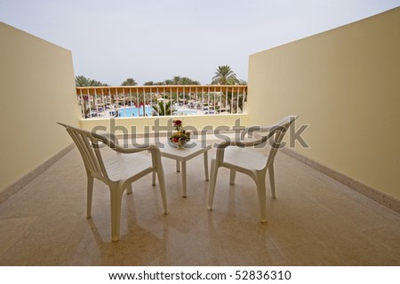 Table and chairs on a balcony overlooking a swimming pool