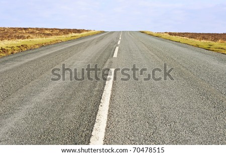 Single lane road in the countryside heading towards horizon
