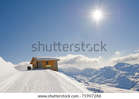 Mountain hut on edge of mountain with landscape view and a skidoo bike