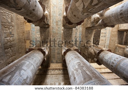 Columns inside an ancient egyptian temple covered in hieroglyphic carvings and paintings