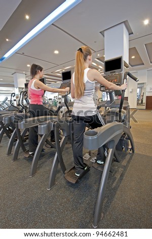 Two young women on step machines at a gym