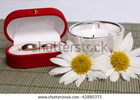 small box with weddings rings next to  candle and camomiles!