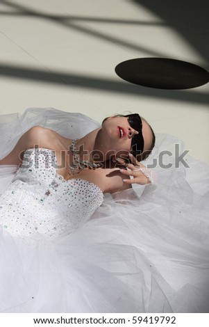 stock photo The beautiful bride in wedding dress sits on floor in sun 