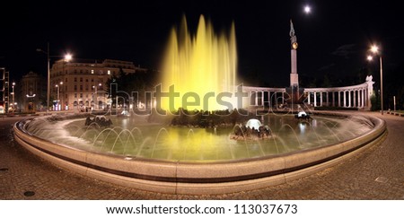 Wide panorama of the colorful World War Fountain and monument in Vienna, by night, under the moon