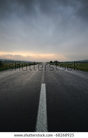 Straight lonely road at sunset after storm