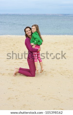 Happy mother and daughter playing at beach.