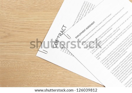 Fastened pages with legal documents on wooden desk.