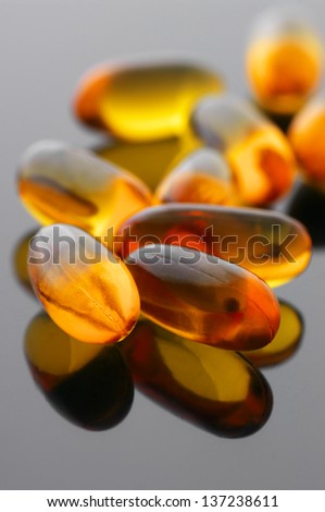 Close-up of fish oil capsules on gray glossy background.
